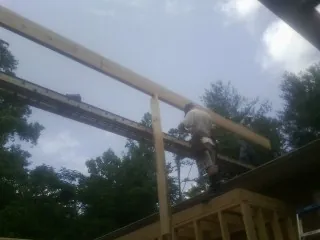 Carpenter setting a ridge beam over a new addition frame — Ice Dam Removal by Roofing Brothers in Comfort