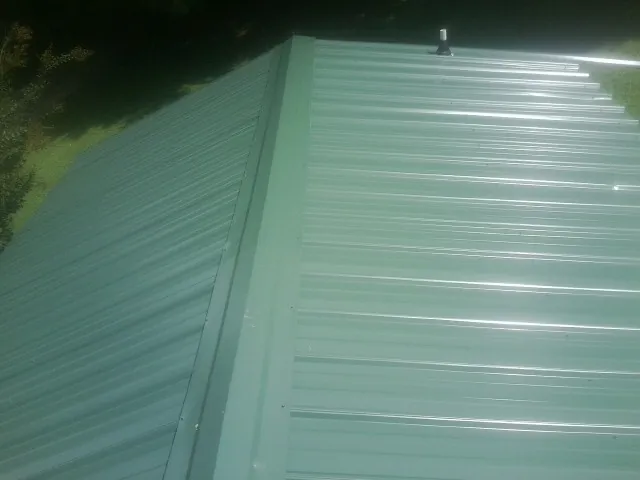 New green metal panels meeting at the ridge of a roof — Flat Roof Repair work by our crew in Comfort