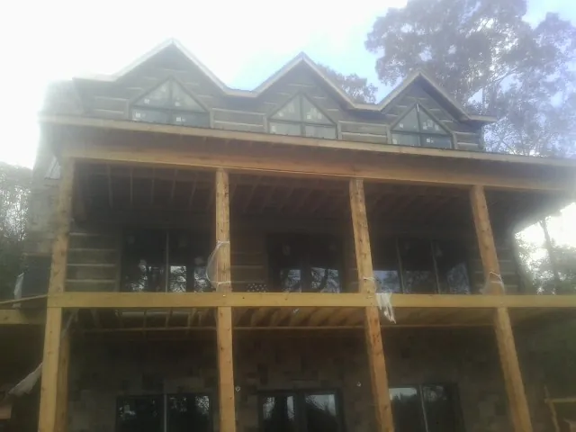 Dormers and porch framing on a large log home under construction — Roof Coating work by our crew in Comfort