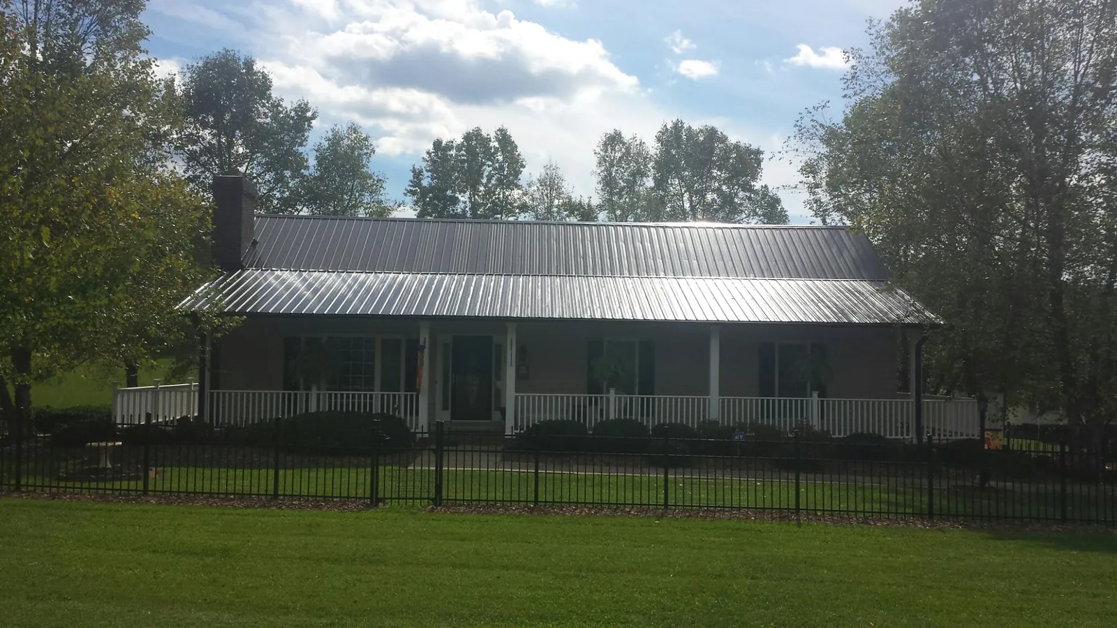 Gray metal roof on a brick ranch with a full width front porch — Gutter Guard Installation work by our crew in Comfort