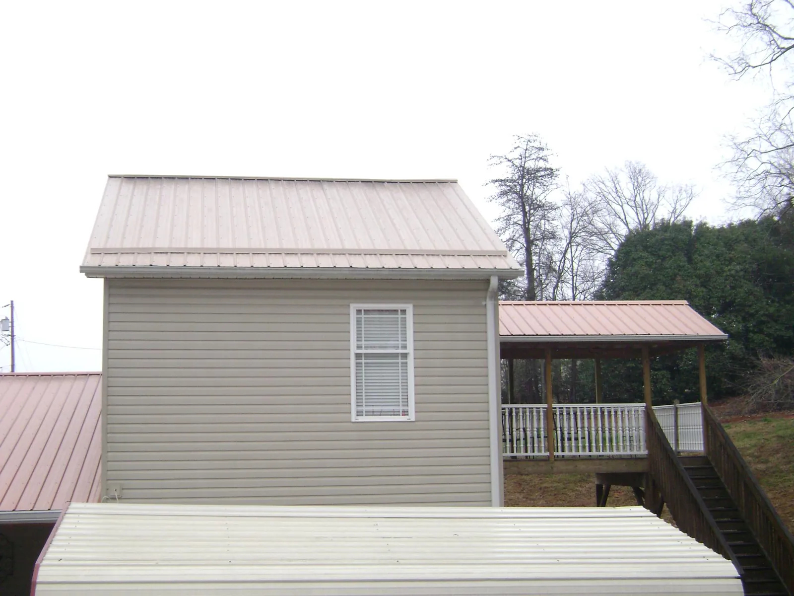 Tan metal roofs on a two story addition and attached porch, from a Roof Replacement job in Comfort
