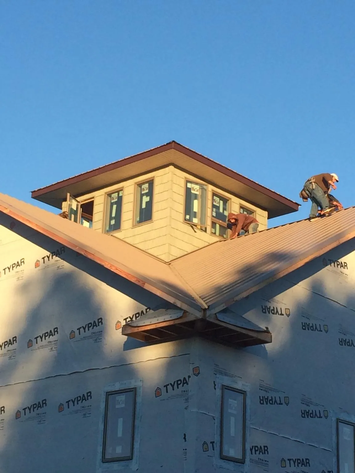 Roofers working around a rooftop cupola on a new metal roof at sunset — Roof Waterproofing in Comfort by Roofing Brothers
